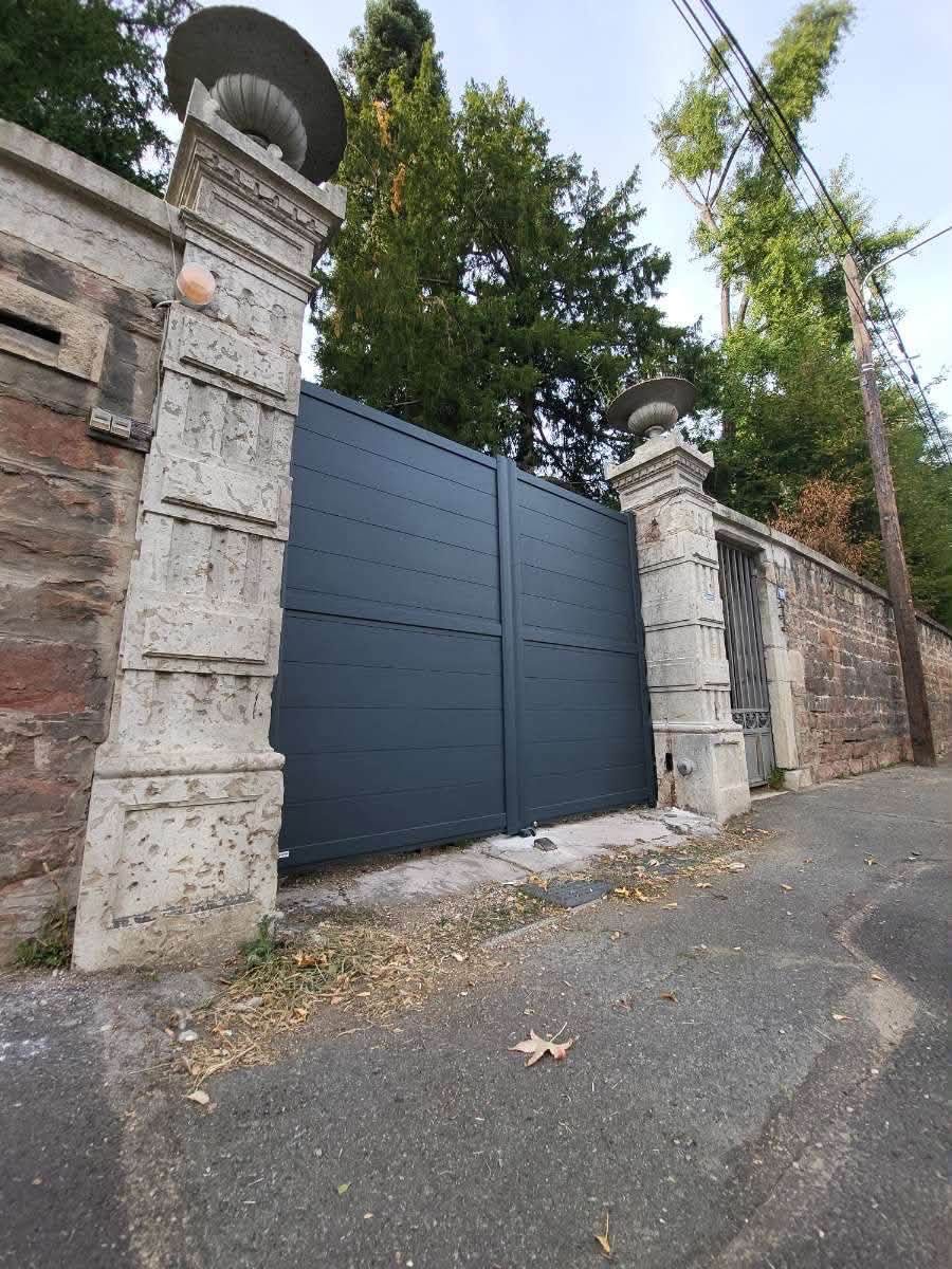 Portail aluminium gris entre piliers en pierre